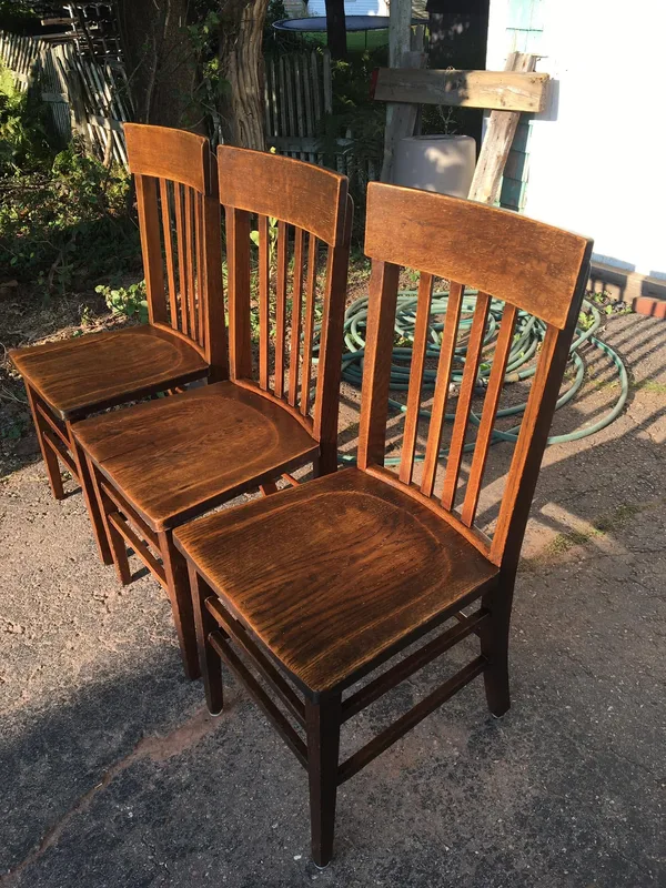 Three wooden slat-back dining chairs outdoors