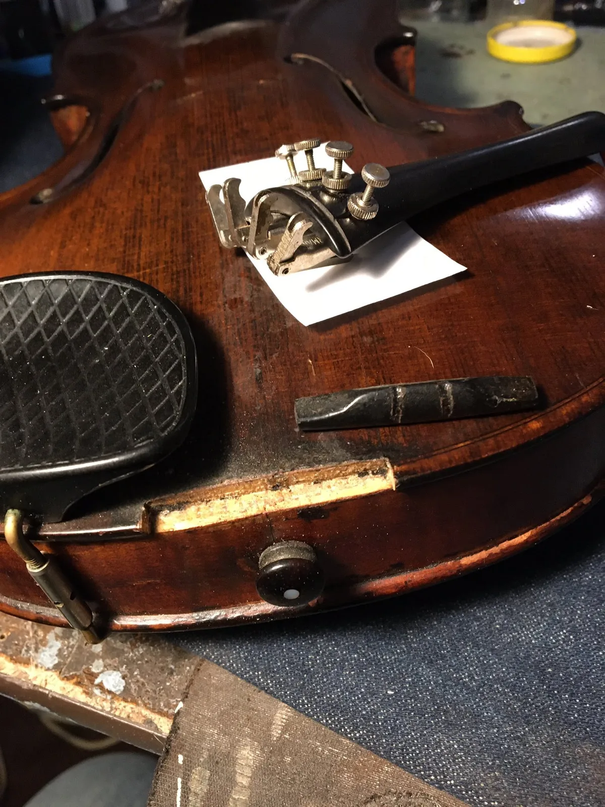Violin with its saddle removed and tailpiece resting on protective paper