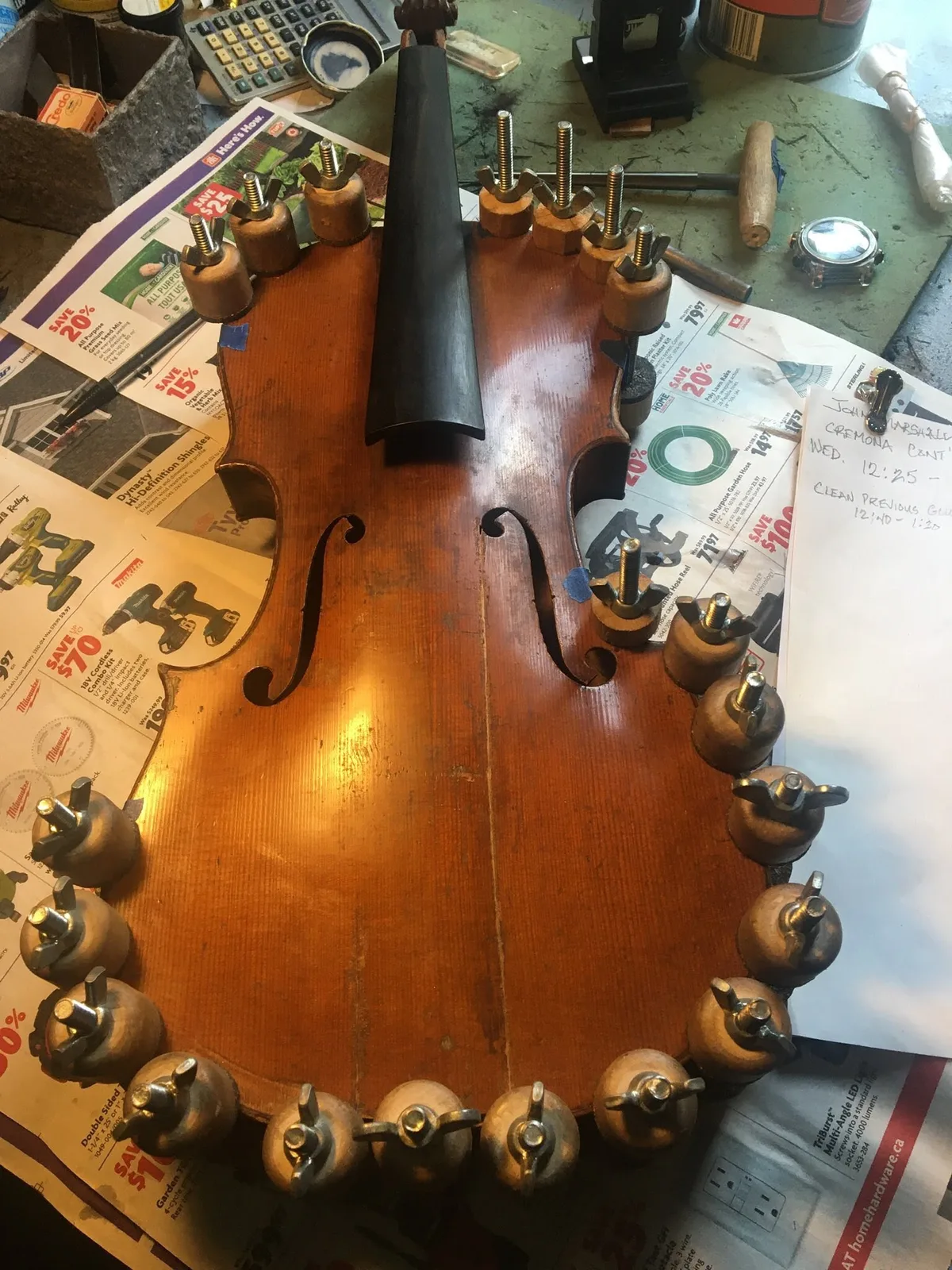 Violin held in spool clamps around the edges during a seam repair