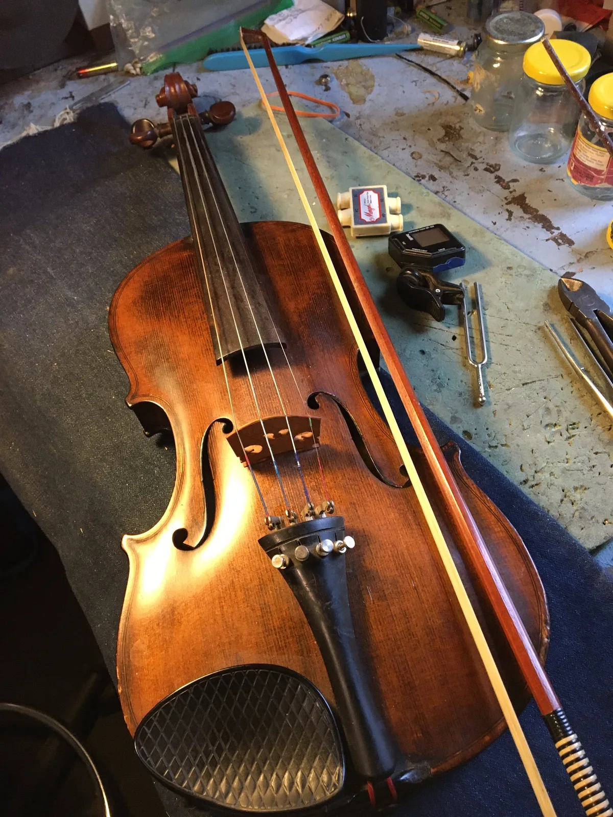 Violin and bow resting on Peter’s instrument repair workbench